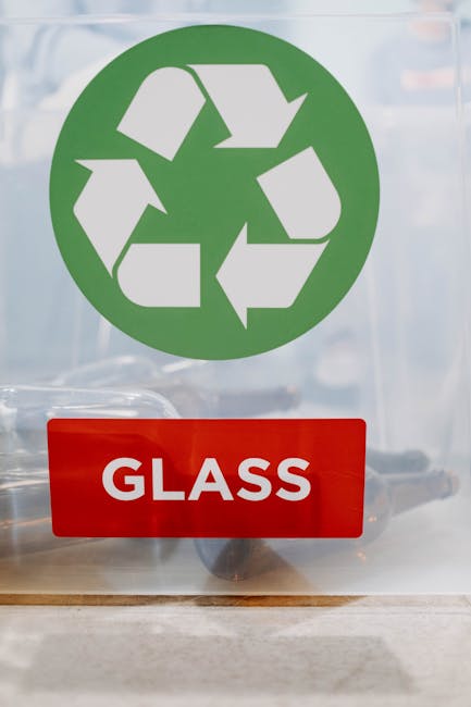 A recycling area with a white metal wall and a blue 'Recycling Only' sign above a collection of cardboard boxes and paper waste. The packaging materials include flattened cardboard boxes, some with vi